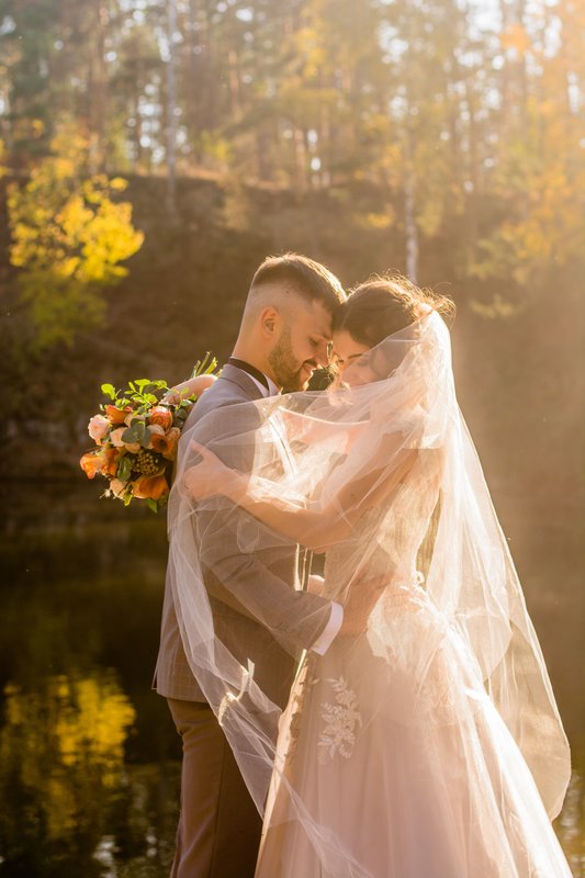 Une photo lumineuse d’un couple, des jeunes mariés avec le voile, une photo souvenir avec une ambiance champêtre pour le jour du mariage 
