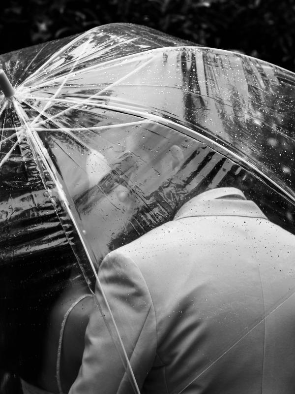 Mariage en Normandie - photographie de deux jeunes mariés s'embrassant sous un parapluie