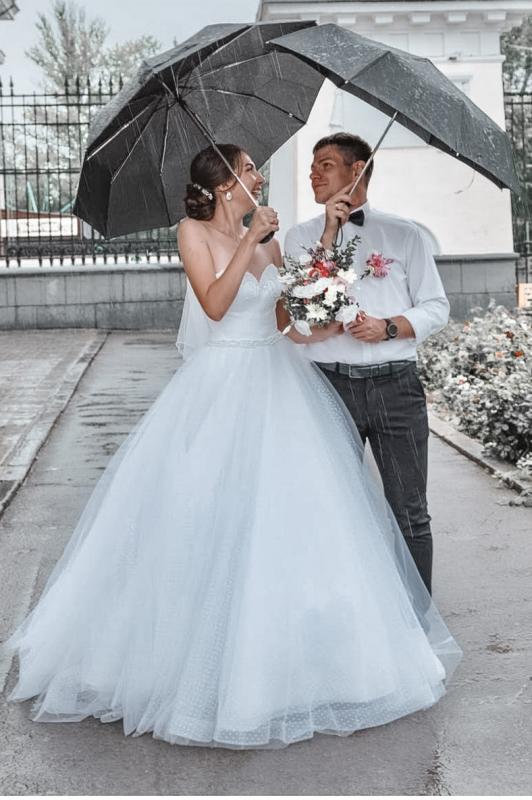 photographie de mariés sortant de leur cérémonie de mariage sous la pluie 